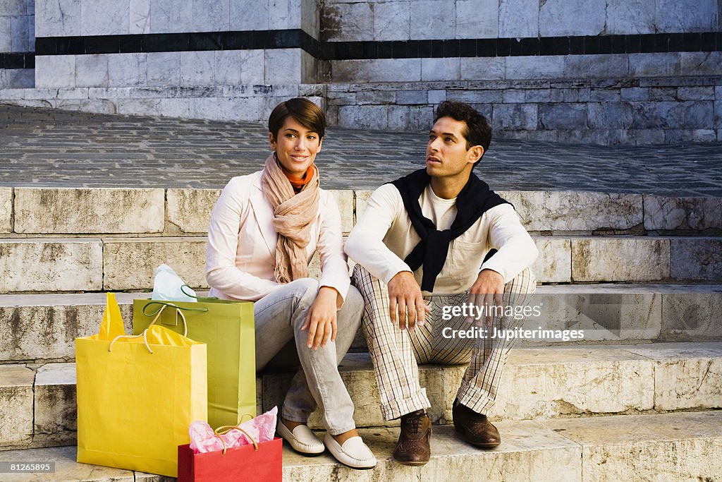 Couple with shopping bags sitting on steps