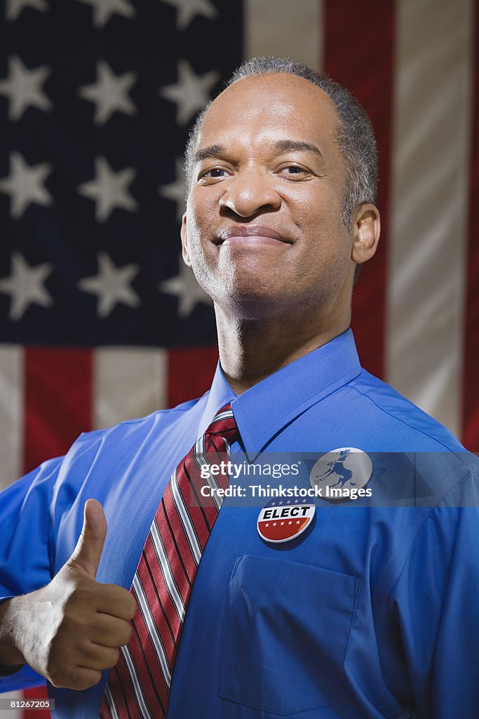 Politician with thumbs up by American flag