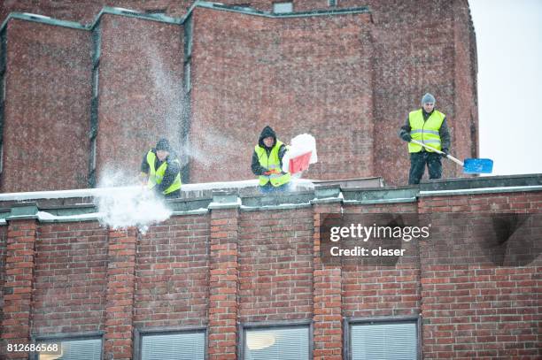 men cleaning rooftop from snow. with showels - snow shovel stock pictures, royalty-free photos & images