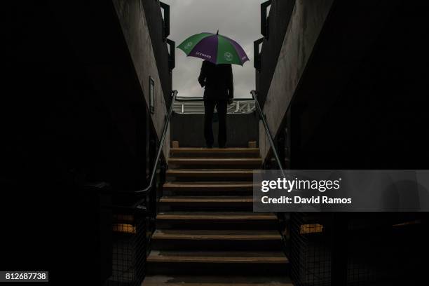 Steward shelters from the rain at court 1 on day eight of the Wimbledon Lawn Tennis Championships at the All England Lawn Tennis and Croquet Club on...