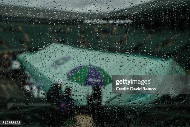 Rain drops are seen on a screen as the covers are seen across court one on day eight of the Wimbledon Lawn Tennis Championships at the All England...