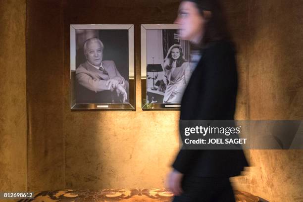 Woman walks past portraits of Lucien Barriere and Diane Barriere, in the newly-renovated Barriere Le Fouquet's Hotel, on the Champs-Elysees avenue in...