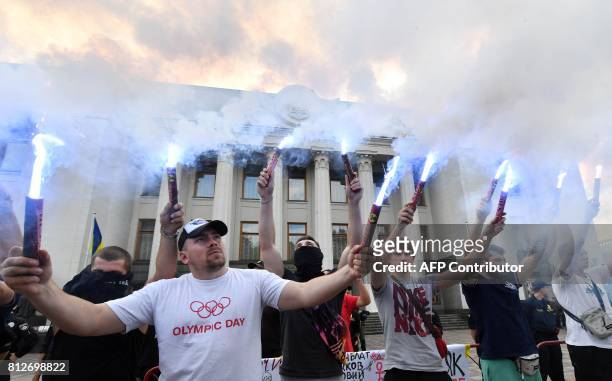 Activists hold up flares as the protest in front of the Ukrainian Parliament in Kiev on July 11, 2017 demanding the removal of immunity for deputies....