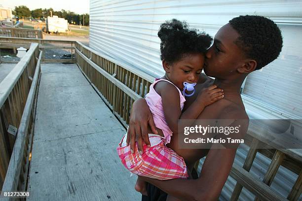 Adrian Cross holds his sister Kailah Smith, 18 months, outside their parents' trailer just before the family moved out of the trailer in FEMA Diamond...
