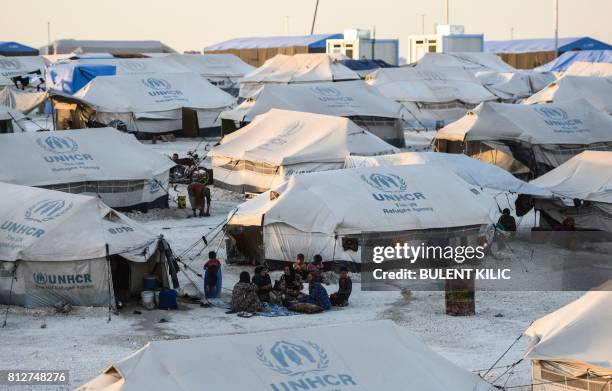 Displaced Syrians who fled the countryside surrounding the Islamic State group's Syrian stronghold of Raqa, have dinner at a temporary camp in the...