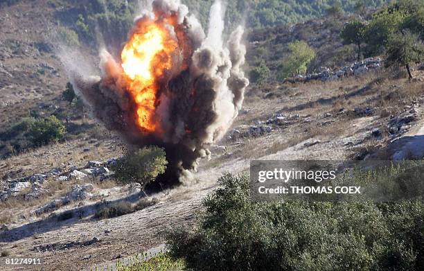 Bomb experts from the Mines Advisory Group explode a cluster bomb after finding it in the southern Lebanese village of Sultaniyeh, 30 August 2006. A...