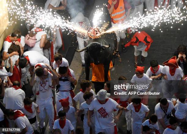 Man wearing a costume of "Toro de Fuego" chases people during the San Fermin Festival on July 11 in Pamplona, northern Spain. / AFP PHOTO / ANDER...