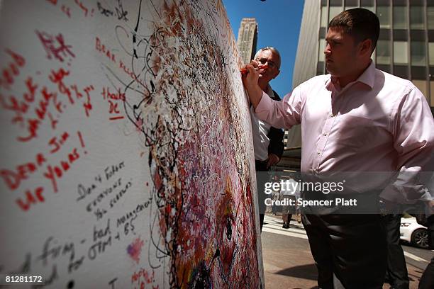 Bear Stearns employee Zachary Nuzzi writes a message on a painted portrait of Bear Stearns CEO James Cayne created by New York artist Geoffrey...