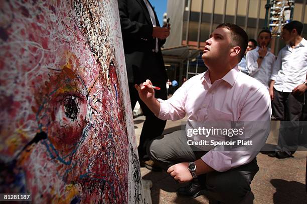 Bear Stearns employee Zachary Nuzzi writes a message on a painted portrait of Bear Stearns CEO James Cayne created by New York artist Geoffrey...