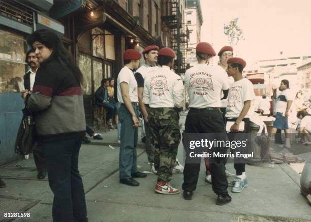 Group of six Guardian Angels talk together on a crowded sidewalk, New York, New York, early 1980s. The Guardian Angels were formed in 1979 as a...