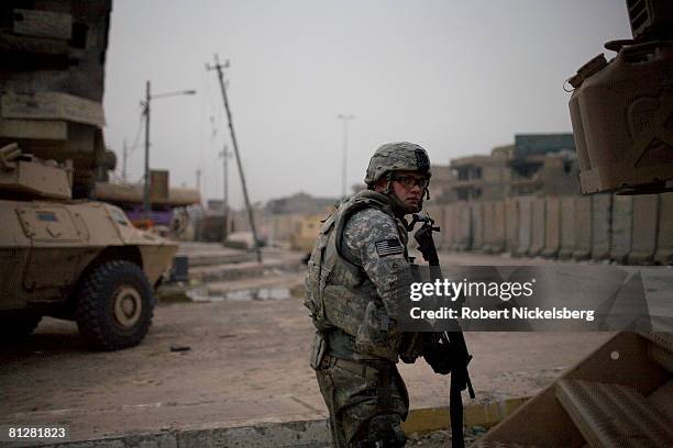 Army soldier from the 3rd Brigade Combat Team, 4th ID looks and listens for an enemy sniper firing across the 12' concrete barrier along Al Quds...