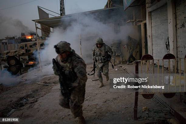 Army soldiers from the 3rd Brigade Combat Team, 4th ID, run back to their vehicles through smoke from an Iraqi Army position after a US Apache...