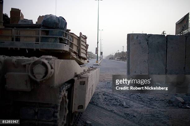 Looking across al-Quds Street, US Army M-1 tanks guard the concrete barrier dividing Sadr City at dawn before Iraqi Armed forces move through to take...
