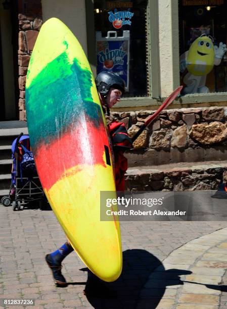 Young man carries his kayak in Vail, Colorado, after competing in the annual GoPro Mountain Games.