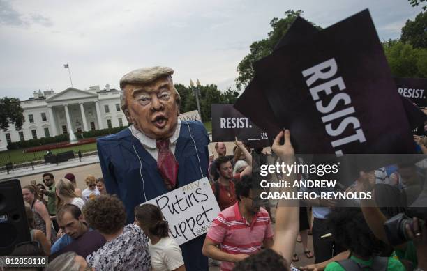 Protesters hold up signs near a US President Donald Trump puppet during a rally calling for accountability for the Trump campaign's alleged collusion...