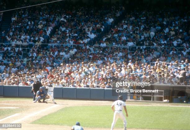 Reggie Jackson of the New York Yankees swings at the pitch as teammate Lou Piniella takes a lead as first baseman Cecil Cooper of the Milwaukee...