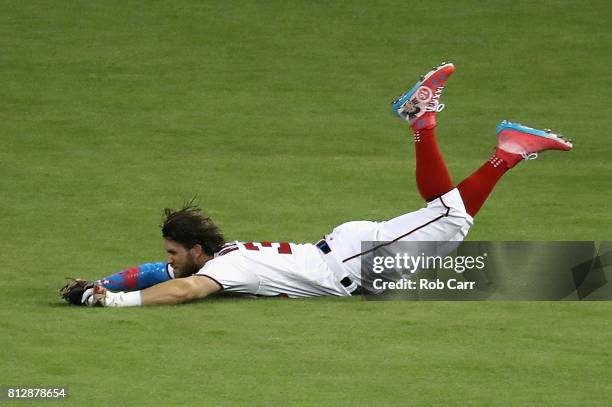 Bryce Harper of the Washington Nationals and the National League catches a ball hit by Salvador Perez of the Kansas City Royals and the American...