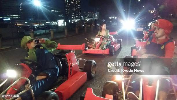 Couple in a group of four Australians takes photos at an intersection during a two-hour go-karts tour in central Tokyo on June 17, 2017. ==Kyodo