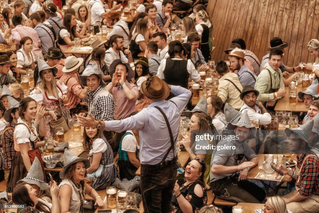 Jóvenes, celebrando en el pabellón de la cerveza en Oktoberfestfest en Múnich