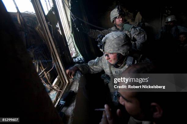 Two US Army soldiers from the 3rd Brigade Combat Team, 4th ID and an Iraqi Army soldier use a laser range finder binoculars to determine a GPS...