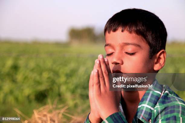 ragazzo dell'età elementare che prega dio - village boy foto e immagini stock