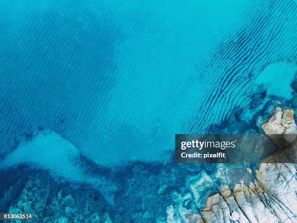 helderblauwe zee en rotsen - cliff texture stockfoto's en -beelden