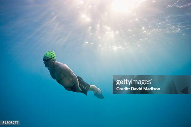 man swimming underwater wearing swim fins. - old people diving stock pictures, royalty-free photos & images