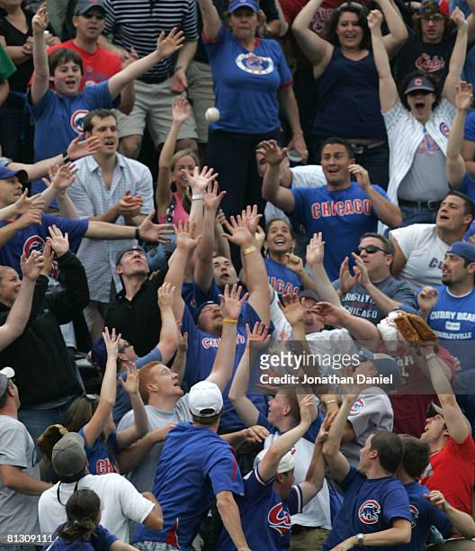 Fans in the left field bleachers clamor for the game-winning home run ball hit by Mark DeRosa of the Chicago Cubs in the 7th inning against the...