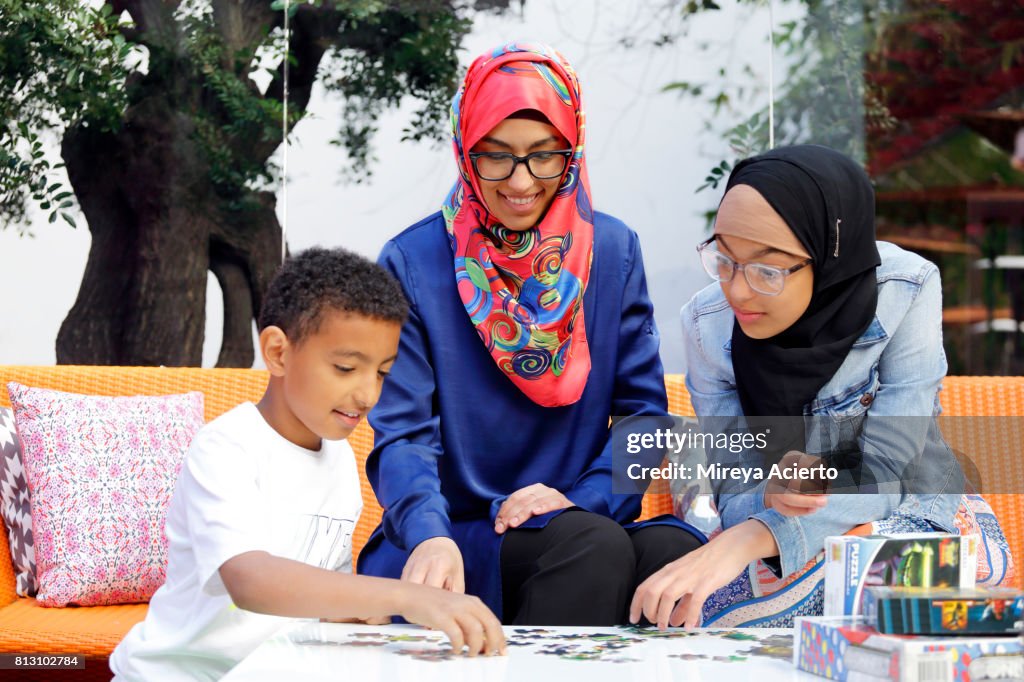 A Muslim-American mother and her two young children playing board games