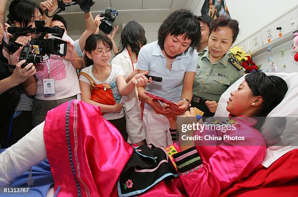 Chinese Olympic champion long-distance runner Wang Junxia talks with an injured earthquake survivor transfered from the quake area in Sichuan...