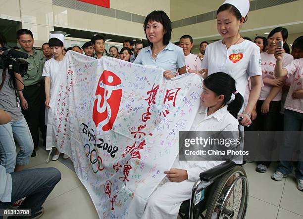 Chinese Olympic champion long-distance runner Wang Junxia displays the Beijing Olympic flag signed with autographs of injured earthquake survivors...