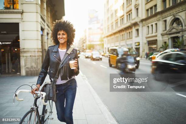 jonge hipster vrouw in de straten van barcelona woon-werkverkeer. - walking with bike stockfoto's en -beelden