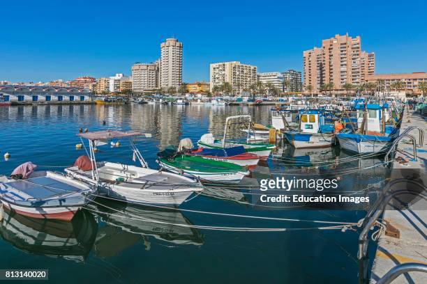 Fuengirola, Costa del Sol, Malaga Province, Andalusia, southern Spain. Fishing boats in the port. Hotels and apartment blocks behind.