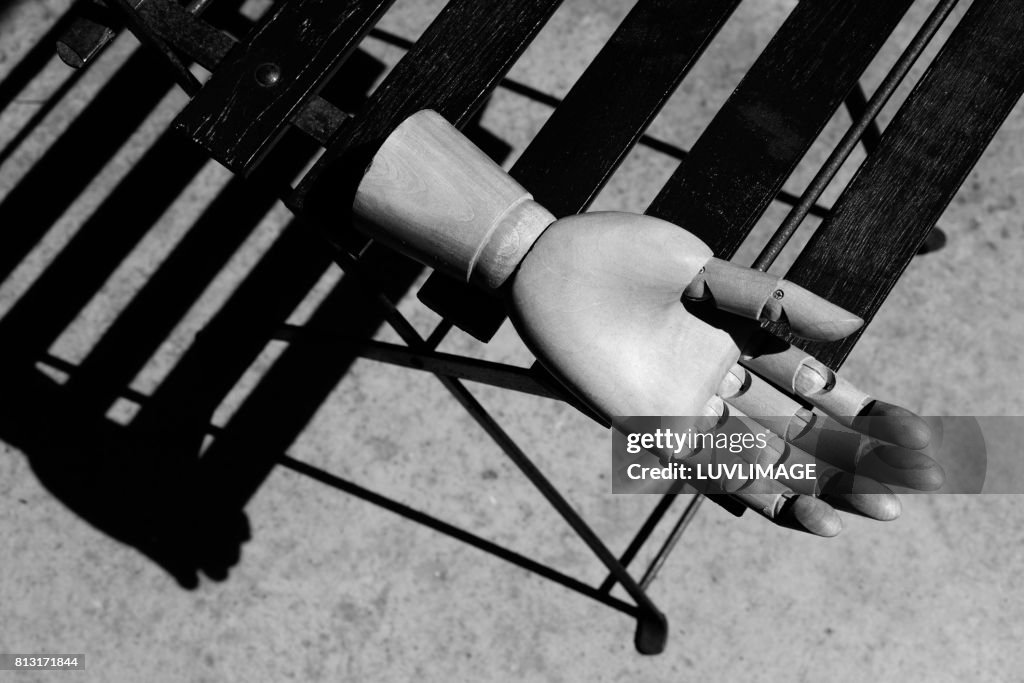 Wooden hand on chair in sunlit scene.