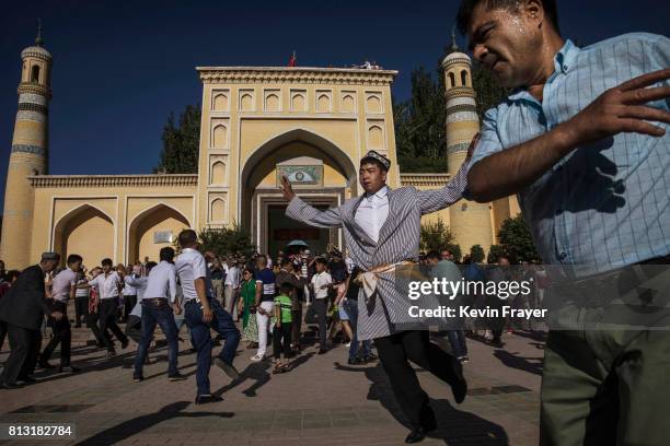 Ethnic Uyghur men who were organized by local party officials, dance after prayers marking Eid Al Fitr outside Id Kah Mosque on June 26, 2017 in the...