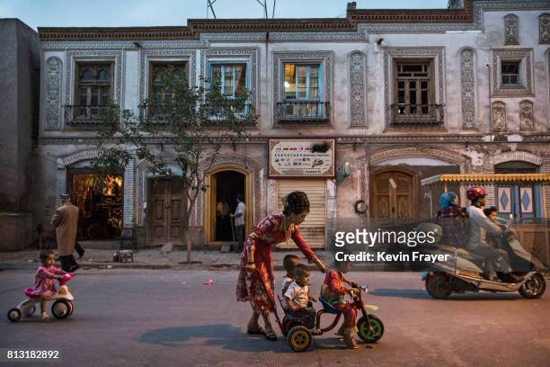 An ethnic Uyghur woman pushes her children on a tricycle on June 28, 2017 in the old town of Kashgar, in the far western Xinjiang province, China....