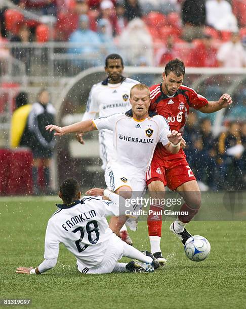 Jarrod Smith of Toronto FC runs for the ball with midfielder Joe Franchino of the L.A. Galaxy and a diving Sean Franklin fending him off during their...