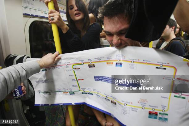 Party reveller bites into a London tube map sticker in a carriage on the London Underground during a Facebook cocktail party on the Circle Line on...