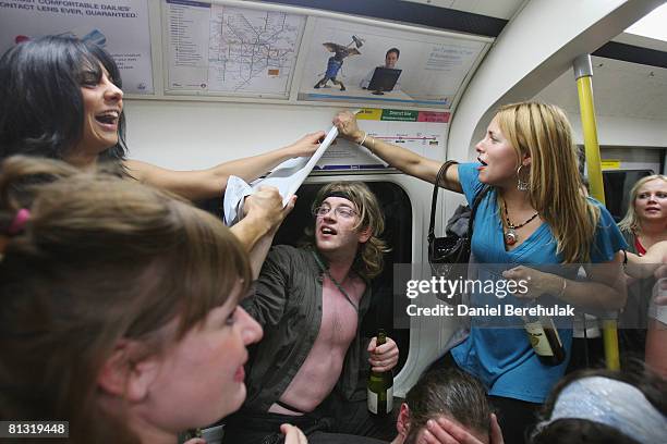 Party revellers remove a London tube map sticker in a carriage on the London Underground during a Facebook cocktail party on the Circle Line on May...