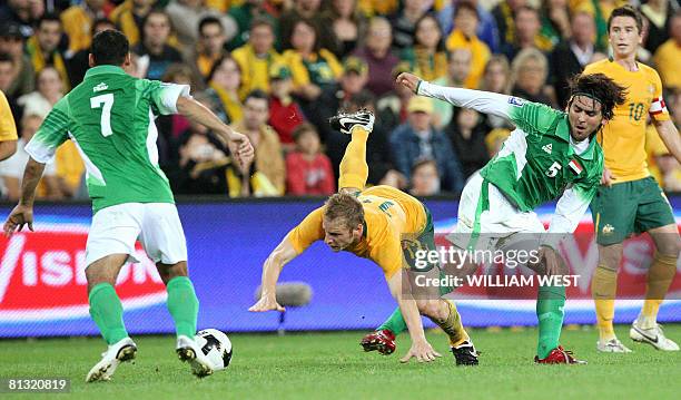 Australia's Vince Grella is tackled by Iraq's Emad Rida and Nashat Akram Abid Ali during their World Cup qualifying football match in Brisbane on...