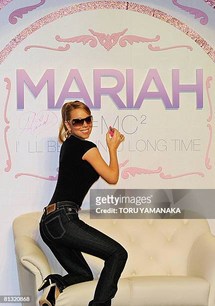 Pop star Mariah Carey poses for fans after signing her autograph on a board during an event to promote her new album "E=MC2" in Tokyo on June 1,...
