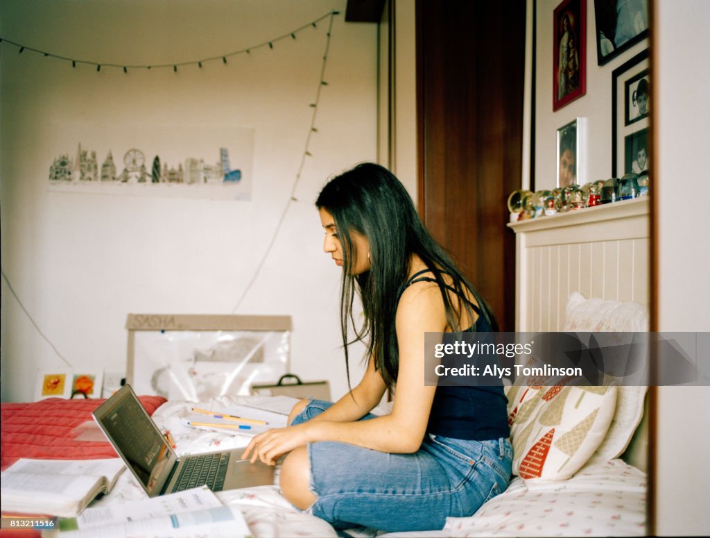 Profile shot of teenage girl in her bedroom, working on laptop