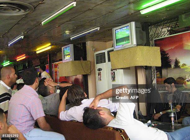 Iraqis react as they watch the World Cup qualifying match between Iraq and Australia at a coffee lounge in Baghdad on June 1, 2008. Australia's Harry...