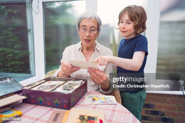 grandmother and grandson looking through old photographs - gran stock pictures, royalty-free photos & images