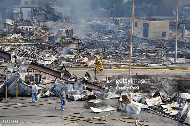 Firefighters walk past debris after approximately 400 firefighters from the Los Angeles area battled a huge fire on the backlot of Universal Studios...