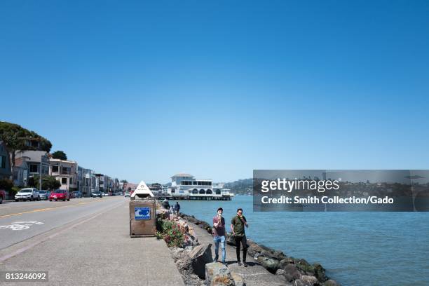 Two men walk along a seawall and eat ice cream cones on Bridgeway Road in the San Francisco Bay Area town of Sausalito, California, June 29, 2017. .