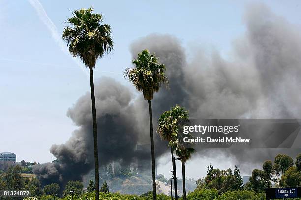 Smoke rises behind palm tress near Gate Four after four as hundreds of firefighters battle a huge fire on the backlot of Universal Studios on June 1,...