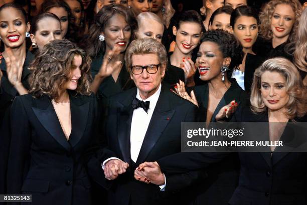 French designer Yves Saint-Laurent salutes the crowd with French model Laetitia Casta and French actress Catherine Deneuve at the Centre Georges...