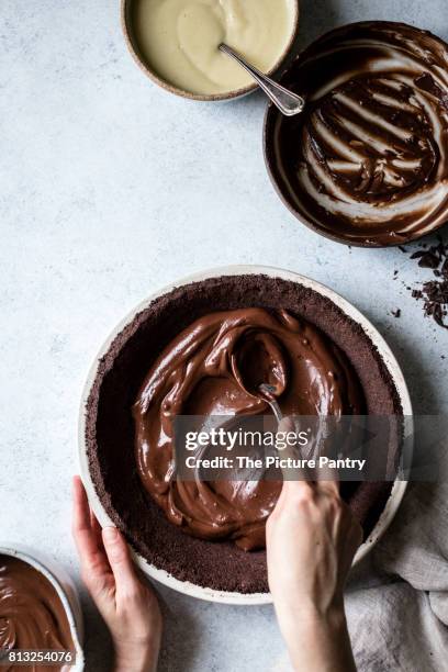 a chocolate pie base being filled with melted chocolate - chocolate pie stockfoto's en -beelden