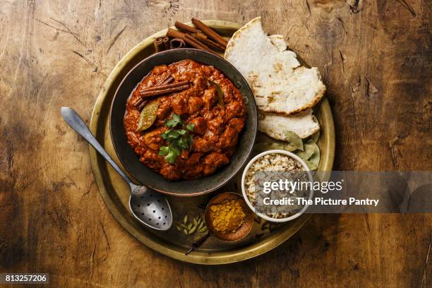 chicken tikka masala spicy curry meat food in copper pan with rice and naan bread on wooden background - tikka masala stockfoto's en -beelden